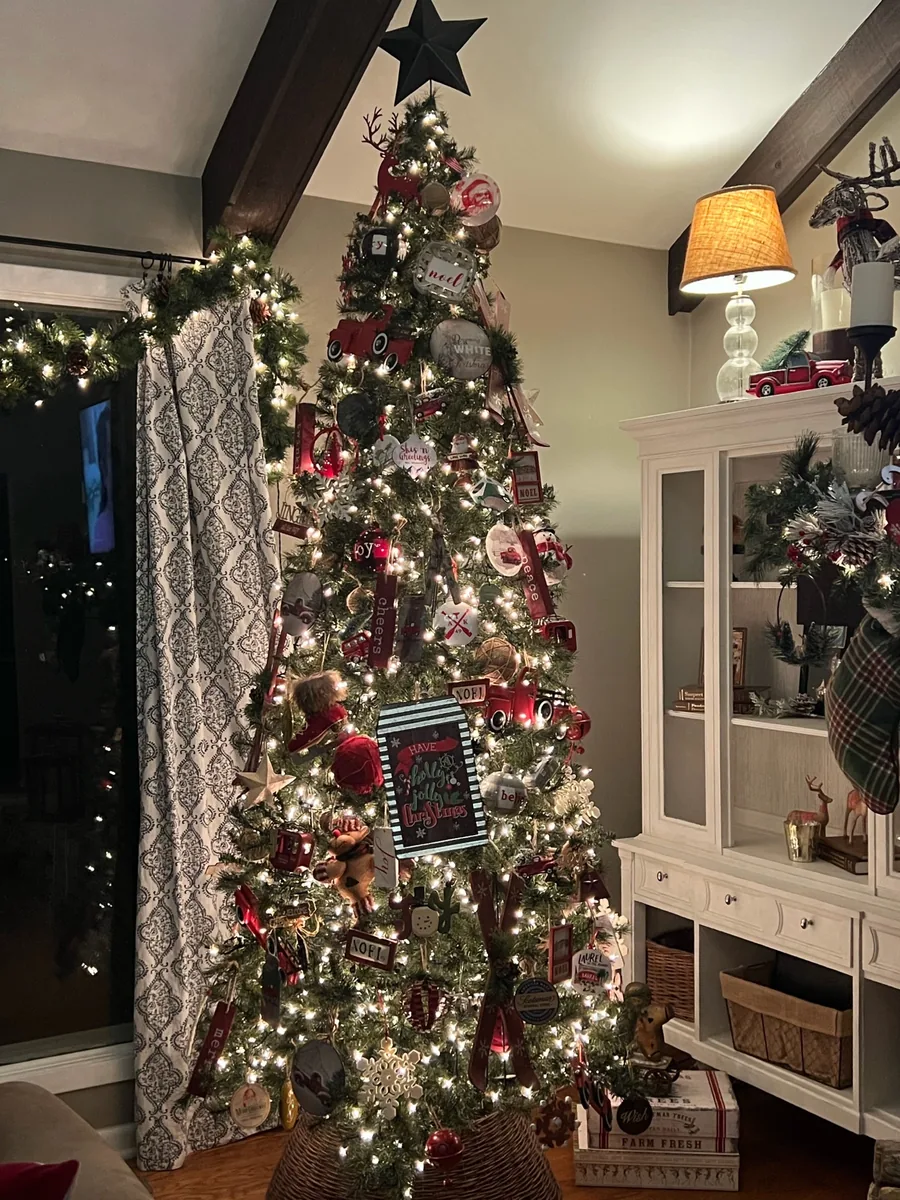 A decorated Christmas tree and a garland-draped stone fireplace create a festive living-room scene.